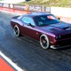 A purple Dodge Challenger muscle car at a drag strip